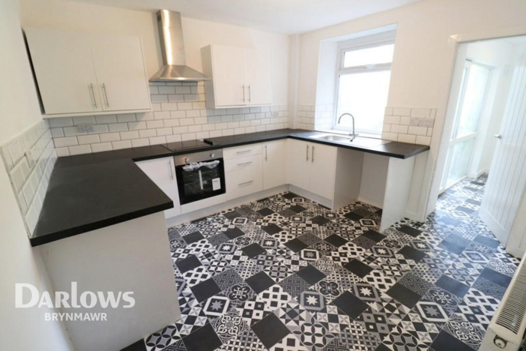 Newly refurbished kitchen with white cabinets and patterned floor tiles in South Wales flip property